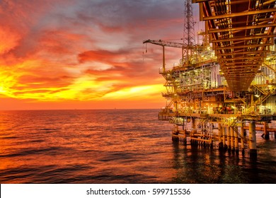 Offshore oil and rig platform in sunset or sunrise time. Construction of production process in the sea. Power energy of the world.