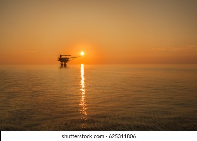 Offshore oil rig  platform in sunset or sunrise time. Construction of production process in the sea. Power energy of the world.