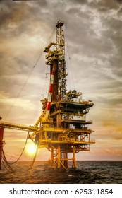 Offshore oil rig  platform in sunset or sunrise time. Construction of production process in the sea. Power energy of the world.