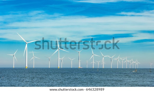 Offshore and onshore\
windmill park ,Windmill farm green energy at sea,Windmill turbines\
by the ocean