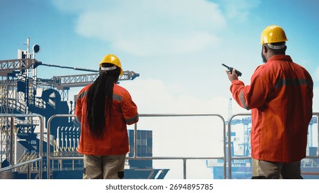 Offshore platform engineer reports operation status using walkie talkie, following safety protocols. African american man in charge of drilling rig communications doing checkup on equipment,