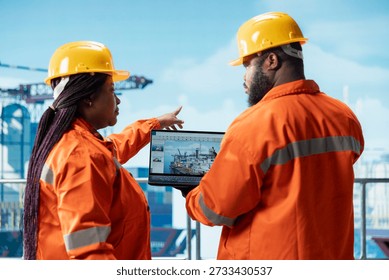Offshore platform engineering team using laptop software interface to track production efficiency. Drilling rig crew uses notebook program dashboard to check equipment sensor readings