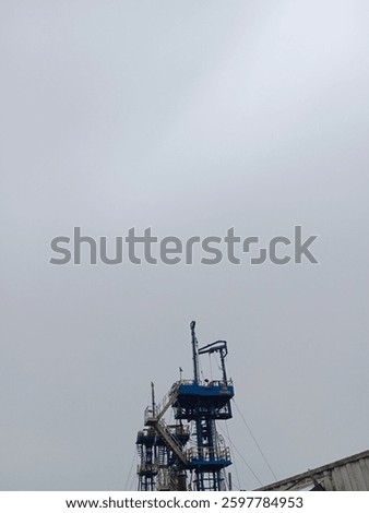 An offshore rig reaching into the overcast sky, a symbol of human ingenuity and engineering resilience in the energy sector.