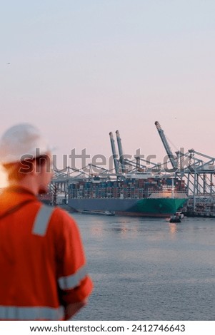 Offshore technician. Seafarer. Seaman. Navigator. A Man In A Boiler Suit Is Standing In Front Of The Port. Seafarer In Front Of The Container Terminal.
