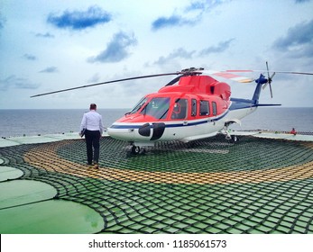 Offshore-Transporthubschrauber und Pilot oder Offshore-Offshore-Hubschrauber Der Hubschrauber landete auf der Bohrinsel, auf See, wechselnde Arbeitsgruppe, an der Bohrplattform auf See, um nach Hause zurückzukehren.Der Hubschrauber auf Offshore-Hubschrauber