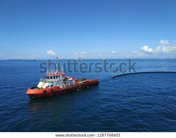 An offshore vessel\
performing oil spill response exercise in the middle of the sea.\
Oil spill response comprises of mother boat and a tow boat to carry\
oil spill boom. 