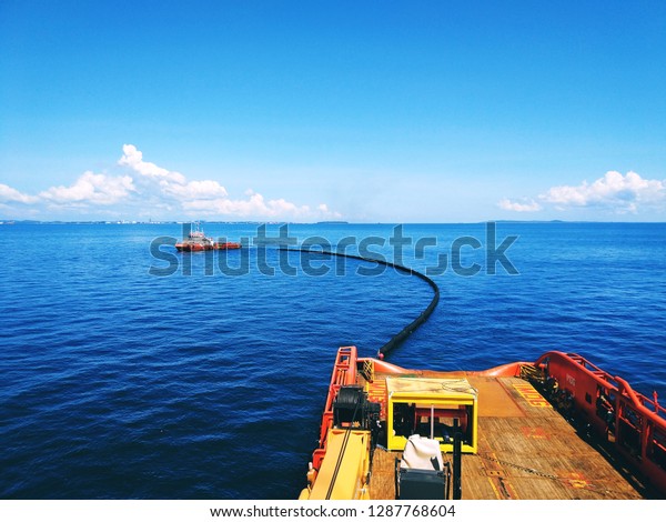 An offshore vessel\
performing oil spill response exercise in the middle of the sea.\
Oil spill response comprises of mother boat and a tow boat to carry\
oil spill boom. 