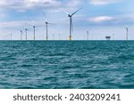 Offshore wind farm across the water under cloudy sky