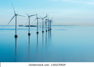 offshore windmill park alternative energy. windmills in the sea with reflection in the morning, denmark