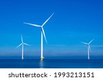 offshore windmill park with clouds and a blue sky, windmill park in the ocean aerial view with wind turbine Flevoland Netherlands Ijsselmeer. Green energy 