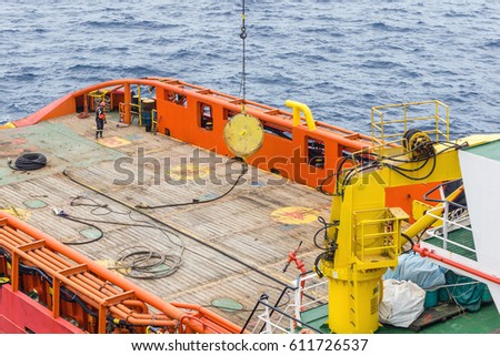 Offshore worker handling an anchor lifted from a construction barge, getting ready for anchor deployment at oil field