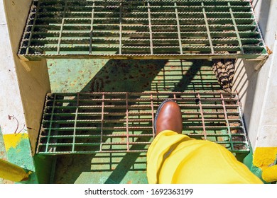 Offshore worker step on a grating stair of a construction work barge