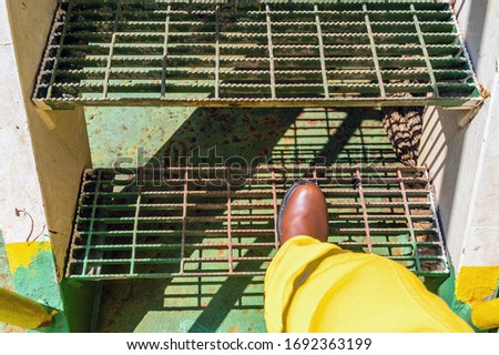 Offshore worker step on a grating stair of a construction work barge