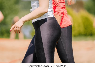 Ogre, Letonia - 21 de junio de 2025 - Dos mujeres con ropa deportiva caminando al aire libre en un día soleado, se centran en licras atléticas y estilo de vida activo en un parque o entorno recreativo.