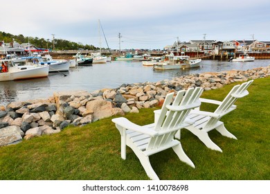 Ogunquit, Maine - May 25, 2019: Two white wooden chairs facing the Perkins Cove, Ogunquit Maine. on a sunny early morning.