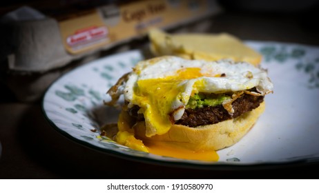 Ogunquit, Maine, USA-February 1, 2021:  An Open Faced Fried Egg With Runny Yoke Sits On Top Of Guacamole And A Veggie Burger Patty Making A Delicious Breakfast Sandwich On A Plate.