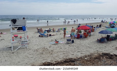 OGUNQUIT, UNITED STATES - Aug 14, 2019: A busy beach with people sitting on deckchairs and swimming in the sea