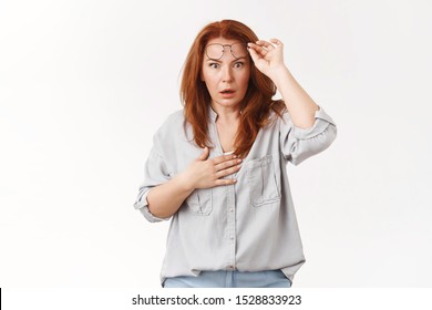 Oh Gosh What Happened. Worried Speechless Stunned Redhead Middle-aged Mother Take-off Glasses Panic Hold Hand Heart Open Mouth Gasping Nervously React Shook Intense Stare Camera White Background