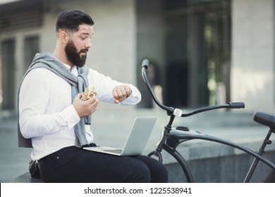 Oh My God, I Am Late. Shocked Businessman Looking At Wristwatch, Having Lunch Break And Working On Laptop Outdoors, Copy Space