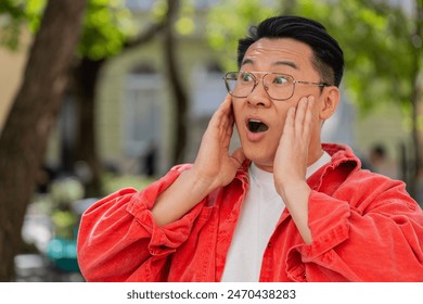 Oh my God, Wow. Asian middle-aged man looking surprised at camera with big open eyes shocked by victory game winning, lottery goal achievement, good news outdoors. Chinese guy on urban city street - Powered by Shutterstock