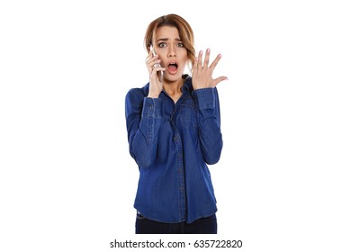 Oh No! Beautiful Young Woman Talking On The Phone Looking At Camera And Looking Shocked Standing On White Background