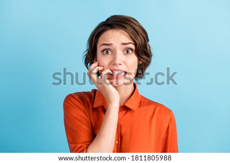 Oh no I failed again. Closeup photo of sad terrified lady horrified facial expression made big mistake feel guilty bite lips fingers wear orange shirt isolated blue color background