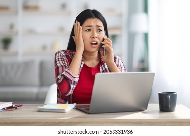 Oh No. Shocked Asian Female Freelancer Talking On Cellphone At Home Office, Frustrated Korean Woman Sitting At Desk With Laptop, Emotionally Reacting To Bad News And Work Problems, Closeup