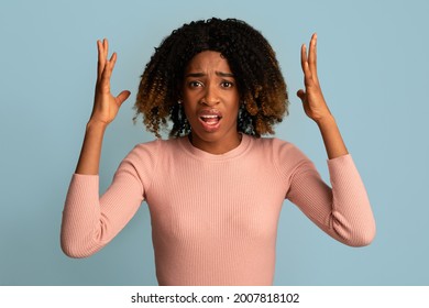 Oh No. Upset African American Lady Raising Hands And Looking At Camera With Sorrow, Unhappy Black Female Emotionally Complaining About Something While Posing Over Blue Background, Copy Space