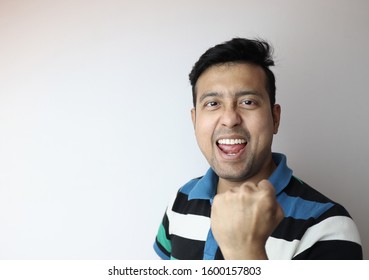 Oh Yeah. Face Of An Asian Man With Clinched Fist Showing Delighted Expression With A Copy Space With Grey Background.