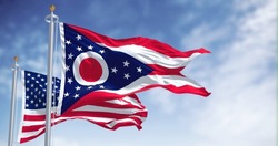 The Ohio State Flag Waving Along With The National Flag Of The United States Of America. In The Background There Is A Clear Sky. Ohio Is A State In The Midwestern Region Of The United States