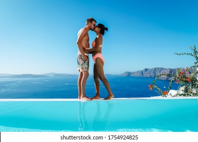 Oia Santorini, couple on a luxury vacation in Greece, Oia Santorini men and woman at caldera infinity pool looking out over the ocean of Santorini Island