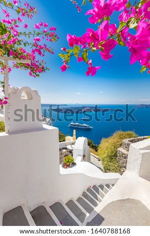 Oia town on Santorini island, Greece. Traditional famous white blue houses wih flowers under sunny weather over the Caldera, Aegean sea. Beautiful summer landscape, sea view, luxury travel vacation