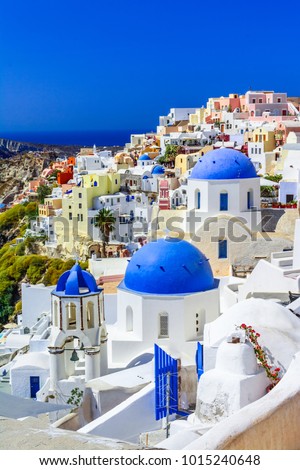 Oia town, Santorini island, Greece at sunset. Traditional and famous white houses and churches  with blue domes over the Caldera, Aegean sea.