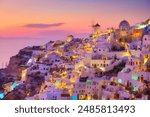 Oia village, Santorini, Greece. View of traditional houses in Santorini. Small narrow streets and rooftops of houses, churches and hotels. Landscape during sunset. 