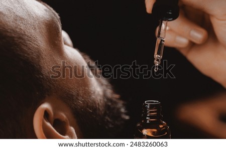 Oil for beard in dropper, process of moisturizing skin, cosmetic for growth hair of man.