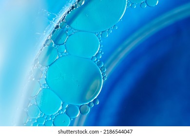 Oil Bubbles And Soap Water In A Glass Bowl With Shades Of Blue Backdrop.