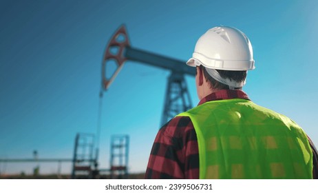 oil business. a worker works next to an oil pump and inspecting it. lifestyle industry business oil and gas concept. engineer studying oil production and talking on the phone with a colleague - Powered by Shutterstock