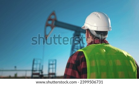 oil business. a worker works next to an oil pump and inspecting it. lifestyle industry business oil and gas concept. engineer studying oil production and talking on the phone with a colleague