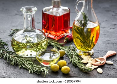 oil in carafe with spices, olives and chili on stone background