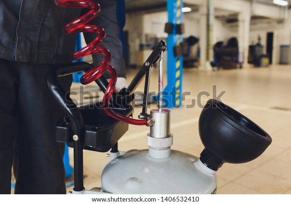 Oil change in automatic transmission.\
Filling the oil through the hose. Car maintenance station. Red gear\
oil. The hands of the car mechanic in\
oil.