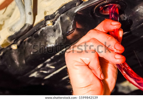 Oil change in automatic transmission.
Filling the oil through the hose. Car maintenance station. Red gear
oil. The hands of the car mechanic in
oil.