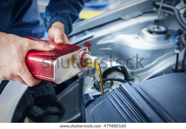 Oil change and car service. Mechanic is\
changing the oil of the car. Act of\
pouring..