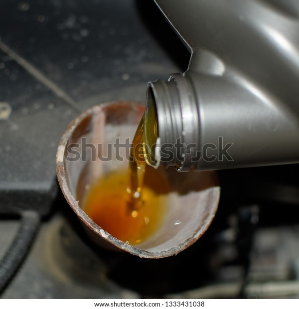 Oil change in the engine\
of the car. Filling the oil through the funnel. Car maintenance\
station