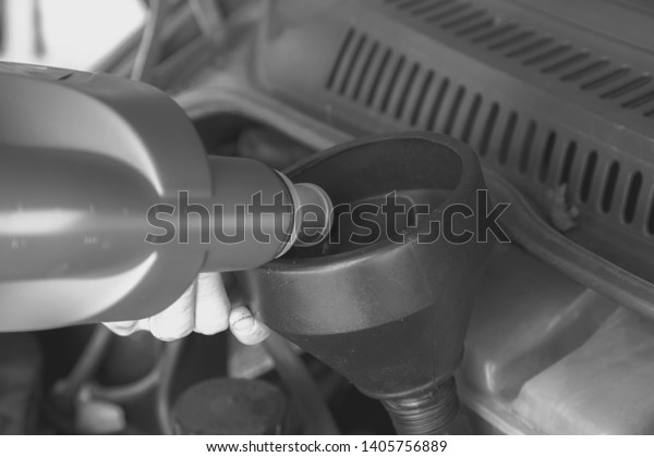 Oil change in the engine\
of the car. Filling the oil through the funnel. Car maintenance\
station.