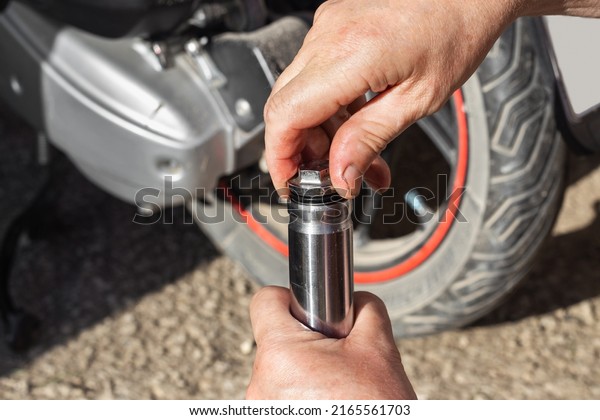 Oil change, motorcycle maintenance and repair.\
A car mechanic unscrews the plug on the shock absorber of the front\
fork of a motorbike.