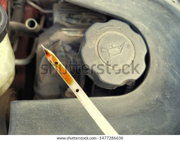 Oil dipstick and oil cap. Oil change. Oil in\
correct level, between minimum and maximum. Car service,\
maintenance. Dusty car engine. Measuring quantity. Measure device.\
Level measurement.