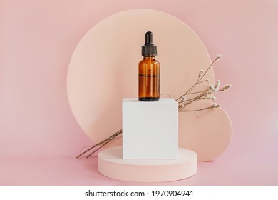 Oil dropper bottle and round podiums with branch of flower.  Beige color background for branding and packaging presentation.  Natural skin care beauty product concept. - Shutterstock ID 1970904941