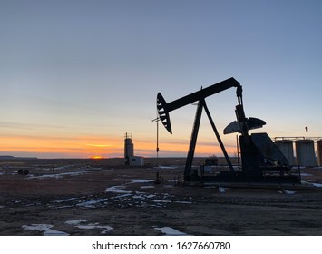 An Oil Field With Pump Jack And Horse Head At Sunset In North Dakota.