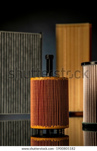 Oil\
filter, fuel filter, cabin filter and air filter, all placed on\
black reflexive glass on gray blue background\
