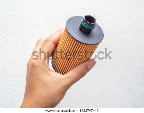 Oil filter. Hand holding car fuel filter\
isolated on white\
background.